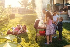 Grandfather teaching his grandchildren how to grill meal.